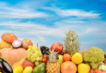 Panoramic photo fruits and vegetables on background clouds and blue sky.