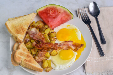 fried eggs with home fries and bacon