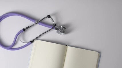 Stethoscope and open notebook with blank page lying on white background, concept of setting health goals for future,