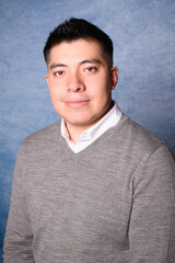 portrait of a serious latin man with gray sweater yearbook style