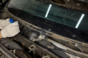 Automobile special workers remove old windscreen or windshield of a car in auto service station garage. Background