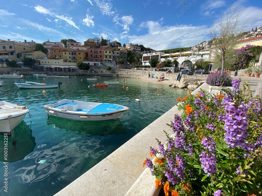 Wall mural embankment of a seaside village with flowers and a boat in the sea