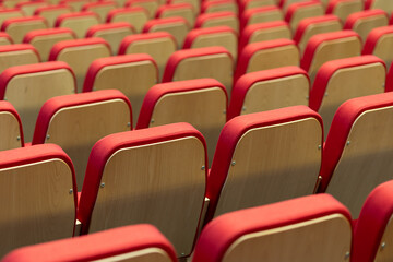 Rows of red and wooden chairs arranged neatly in a large auditorium preparing for an upcoming event...