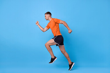 Man in sportswear running on light blue background