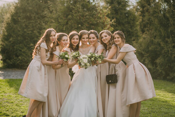 A group of women are posing for a picture, with one of them wearing a white dress. They are all...