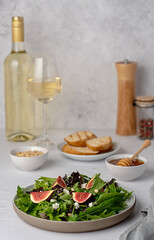 Food photography of salad with fig and feta cheese,  spinach, lettuce, honey, pine nuts, white wine, toasted bread, set table
