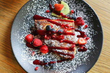 Pancake with mascarpone on a plate. Wooden table fine dining. Topped with powdered sugar, fresh fruits, blueberries, raspberries. Combining sweet and sour flavors. Delicious dessert.