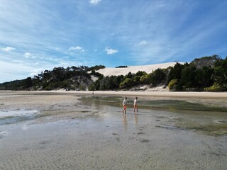 Twin boys playing on the beach at Moreton Island with the big sand dunes in the background