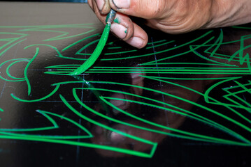 the artist draws a pinstriping styled drawing with a special brush