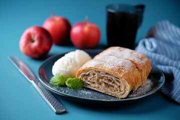 Apple strudel with vanilla ice cream in a plate on a blue background