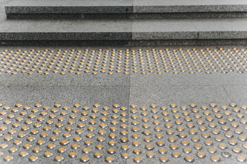 Stainless steel tactile indicators set set on walkway and stairs, closeup. Anti-slip surface.