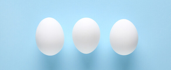 Raw chicken eggs on blue background