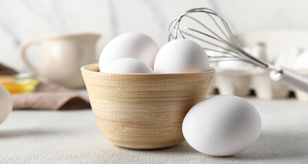 Bowl with raw chicken eggs on white background
