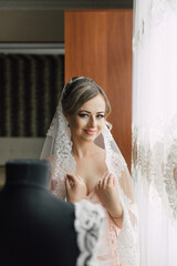 Naklejka premium A woman in a wedding dress is standing in front of a mannequin. She is wearing a veil and is smiling