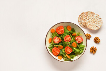 Bowl with fresh vegetable salad and rice crackers on white background