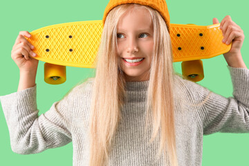 Little girl with skateboard on green background, closeup © Pixel-Shot