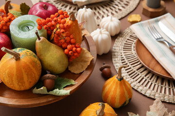 Stylish table setting with candles and autumn decor on brown background