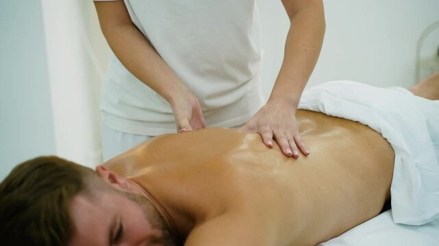 Female Masseuse Performing Back Massage in Spa on Male Client
