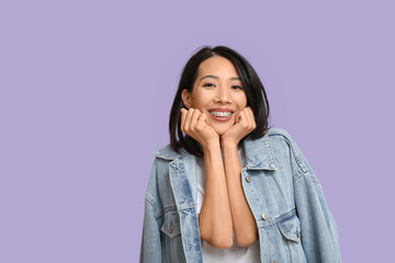 Young Asian woman laughing on lilac background
