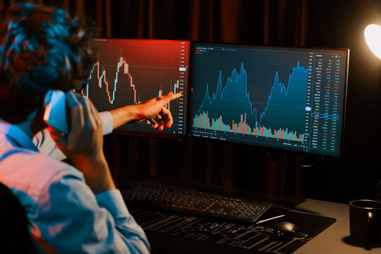 Young investor stock trader calling with broker to invest earning highest profit on current market graph online in real time at neon light modern office, monitor showing investment exchange. Gusher.