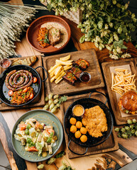 Top view of assorted gourmet dishes with sausage, pork ribs, salad, schnitzel, and burger with fries