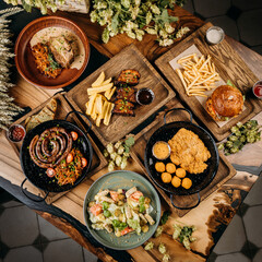 Top view of assorted gourmet dishes with sausage, pork ribs, salad, schnitzel, and burger with fries