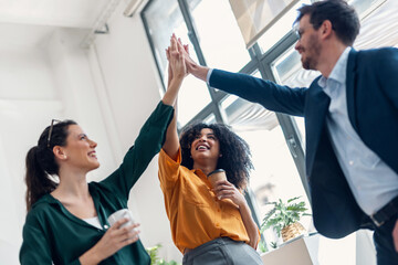 Business team celebrating good job while holding up their right hands on modern startup