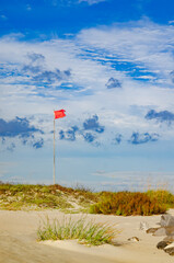 Red flag warning of rough surf in Dauphin Island Alabama, scenic beach view with sea oats