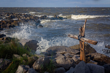 Driftwood cross and rough waves in advance of Hurricane Helene in Dauphin Island Alabama, concept faith, hope or strength