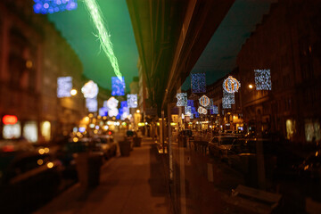 Colorful festive lights illuminate a busy city street at night, reflecting holiday cheer and urban celebrations