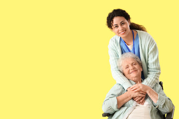 Young African-American female medical worker with elderly woman on wheelchair against yellow background