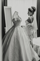 A woman is getting ready for a wedding, and she is standing in front of a dresser with a wedding...