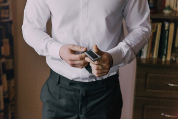 A man in a white shirt is holding a cell phone in his hand. The image has a blurry quality, giving it a somewhat hazy or dreamy appearance