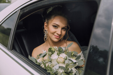 A woman is sitting in a car with a bouquet of flowers in her lap. She is smiling and looking out the window