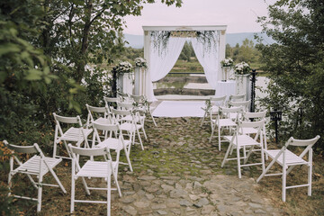 A wedding ceremony is taking place in a beautiful outdoor setting. The ceremony is taking place in...