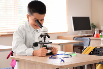 Cute little boy using microscope in science classroom