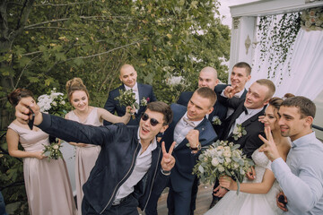 A group of people posing for a picture, one man is taking a selfie with his cell phone
