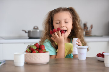 Cute little girl with raspberries and yogurt in kitchen