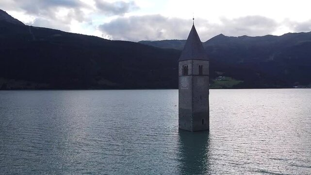 The iconic old church Tower of Graun emerging from the water of the artificial lake of Reschensee in Curon Venosta, South Tyrol, Italy