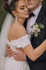 A bride and groom are embracing each other in a wedding photo. The bride is wearing a white dress...