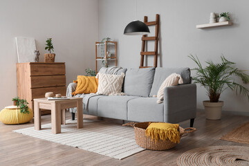 Interior of light living room with wooden ladder, sofa and plants