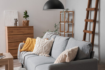 Interior of light living room with wooden ladder, sofa and plants