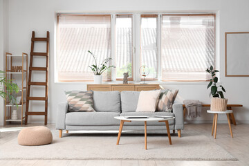 Interior of light living room with wooden ladder, sofa and plants