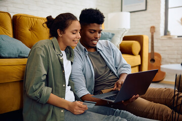 Obraz premium Young happy couple ordering online while using credit card and laptop at home.
