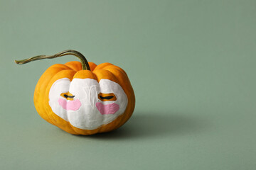 Funny pumpkin with drawn face and cosmetic mask on green background