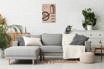 Sofa, pouf, houseplant and coffee table in interior of living room