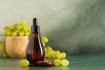 Bottle of cosmetic grape seed oil on green background
