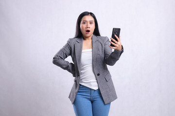 Naklejka premium beautiful young office ladies asia shocked to camera hold waist, holding cellphone wearing gray suit isolated on white background. for technology, lifestyle, shopping, transaction content
