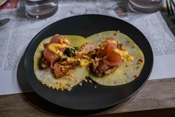 delicious looking tacos topped with pork belly, veggie garnish, and sauces