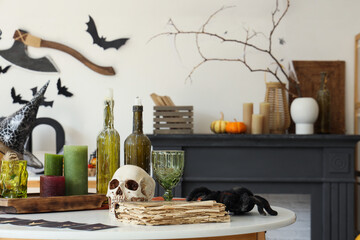 Skull, candles and old book on coffee table in living room. Halloween decoration concept